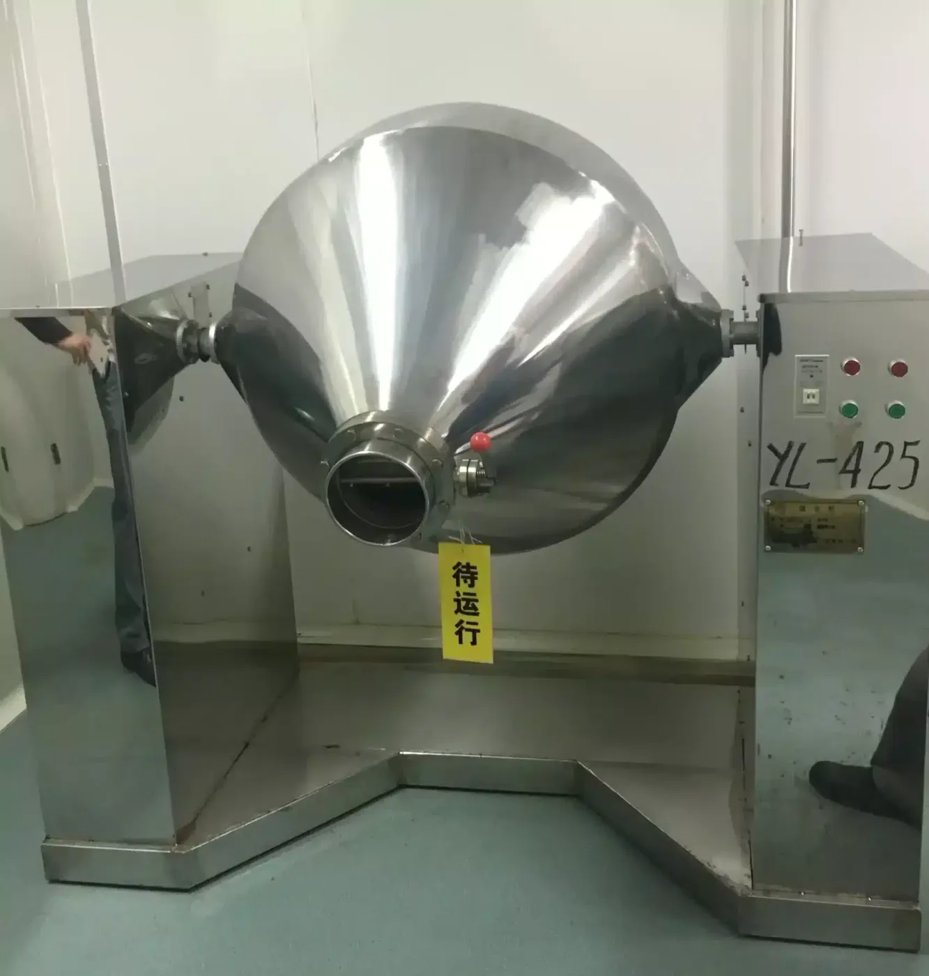 A Double Cone Rotary Vacuum Dryer installed in a clean room, with a shiny stainless steel exterior, control panel, and support frame.