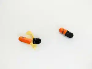 An image of two capsules on a white background, one capsule is partially opened with its orange and black contents spilled out, resembling powder. The other intact capsule has a similar color pattern. Both are marked with 'B6 300mg' signifying their dosage and potential vitamin content.