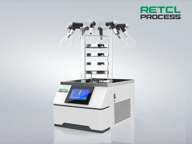 A benchtop freeze dryer from RETL PROCESS with a digital control panel is displayed. The device has a stack of clear chambers connected to a manifold with valves on top, set against a clean, isolated background.