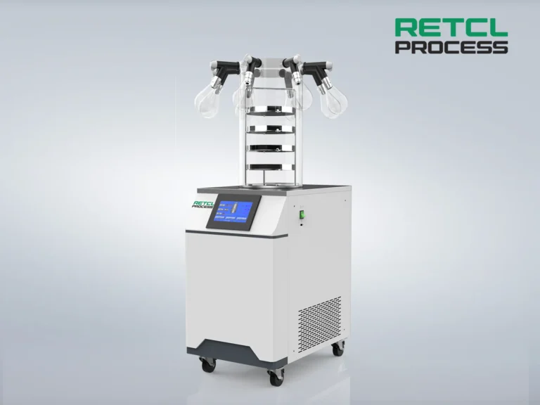 A modern benchtop freeze dryer with multiple chambers and a digital control panel, set against a plain gray background.
